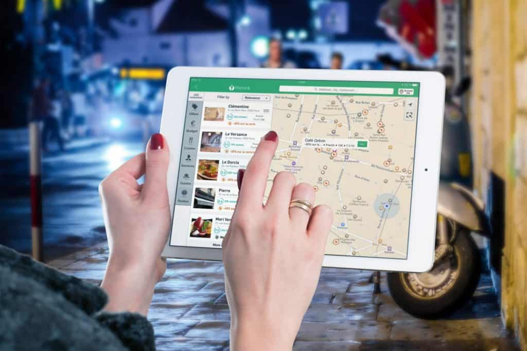 local search business guide - boost visibility & sales Standing on a dimly lit street, a person uses a tablet displaying a city map with marked locations, highlighting why local searches are important for your business, local search business