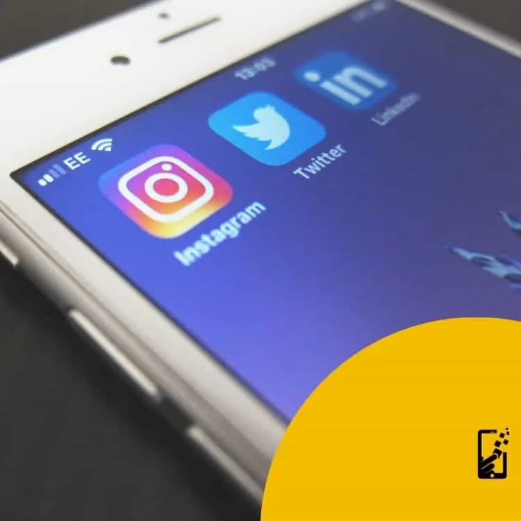 Close-up of a smartphone screen displaying Instagram, Twitter, and LinkedIn app icons—tools of the trade for any social media marketing company. A partial view of the phone and a yellow graphic with a pen icon are visible, instagram boost post
