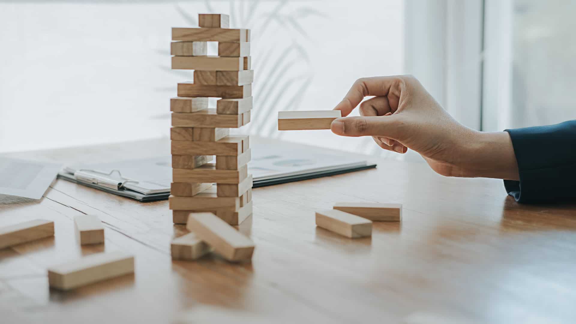 A businessman is building a tower of wooden blocks on a table.