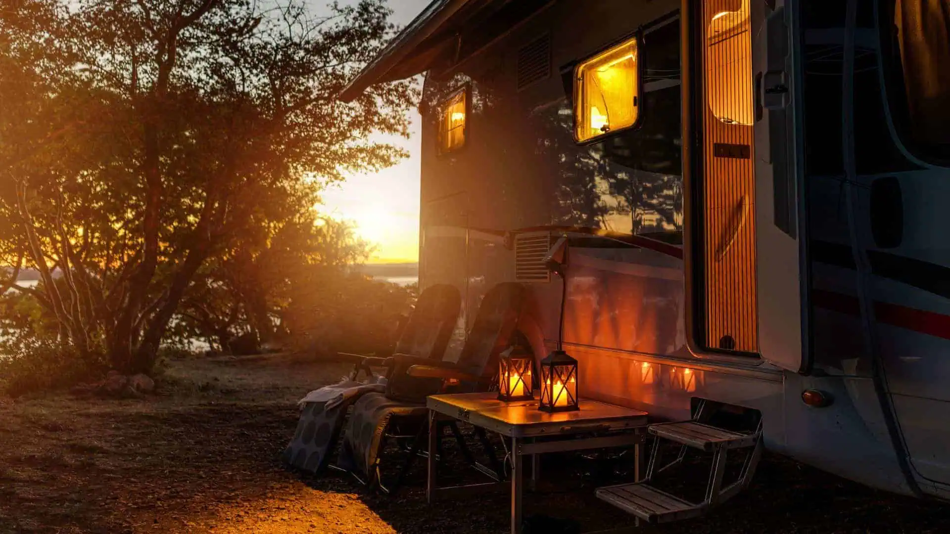 An rv parked in front of a lake at sunset.