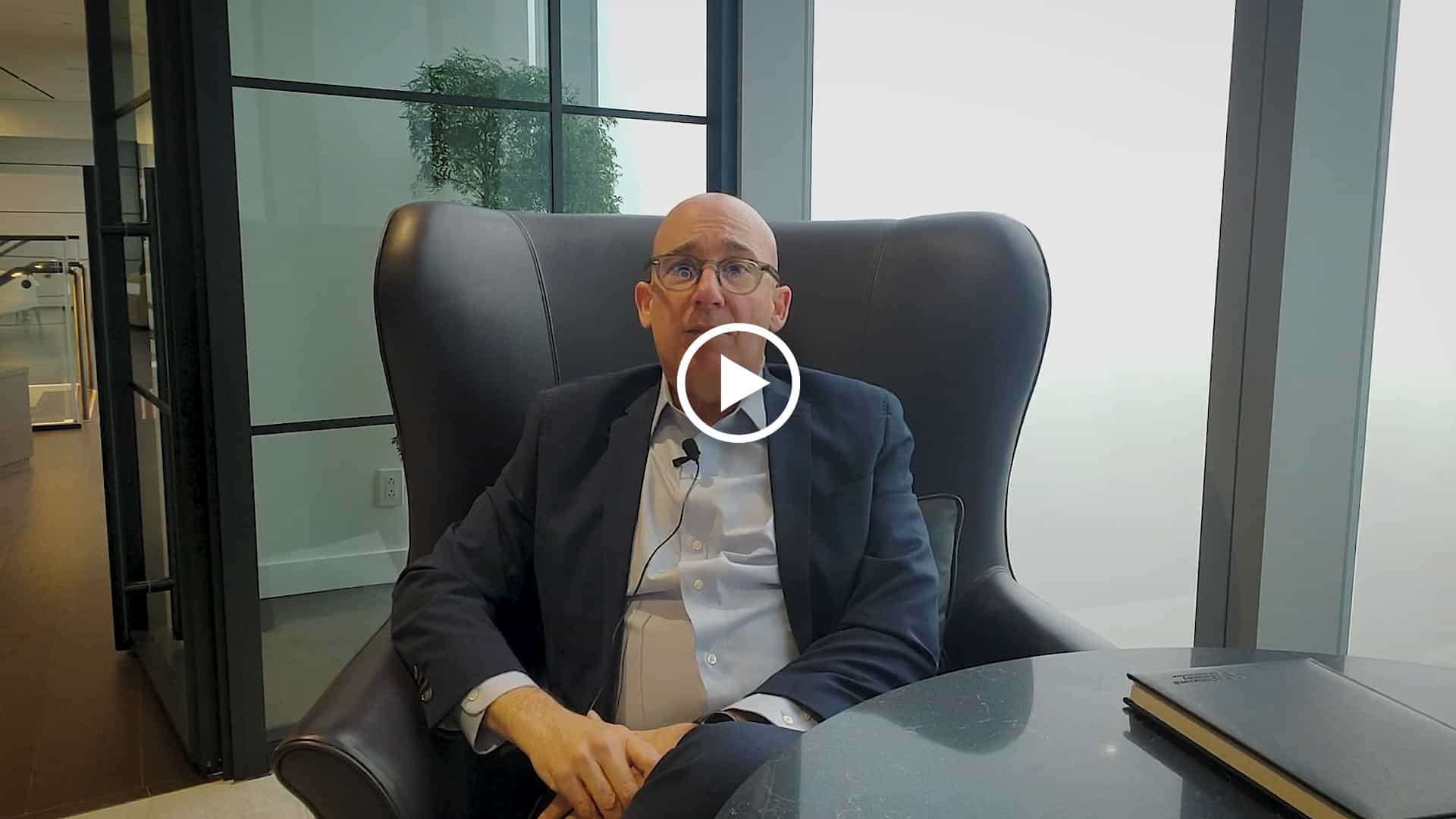 A man in a suit showcasing sample ad creatives while sitting in a chair.