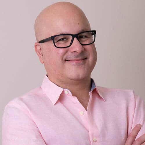A bald man wearing glasses and a pink shirt who works at an Ottawa SEO company.