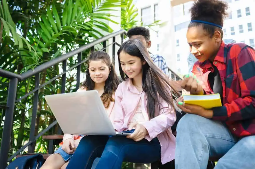 Multiethnic students working on laptops in classroom, popular search, diverse students using laptop Social media profiles
