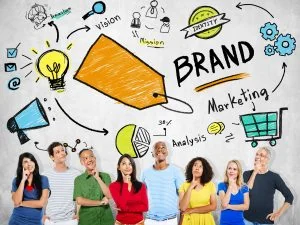 A diverse group of people look up thoughtfully in front of a wall with colorful brand-related doodles and words, reflecting the creative process at a local digital marketing agency.
